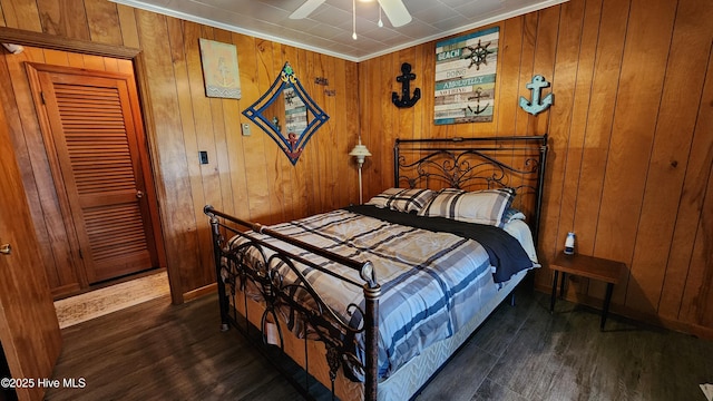 bedroom with ceiling fan, dark hardwood / wood-style floors, ornamental molding, and wooden walls