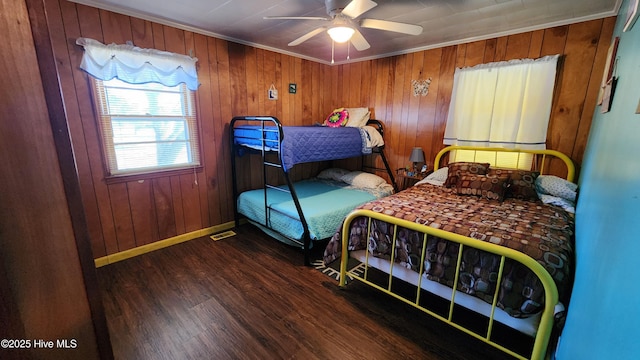 bedroom featuring dark hardwood / wood-style flooring, ceiling fan, crown molding, and wood walls