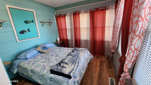 bedroom featuring dark hardwood / wood-style flooring and wooden walls