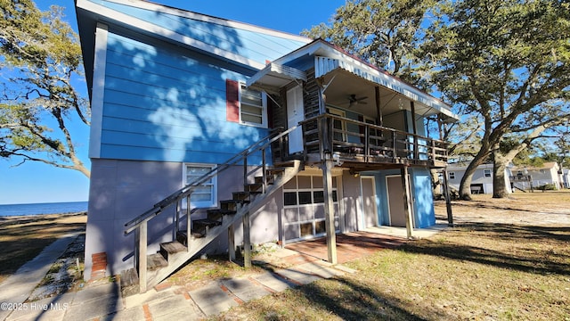 rear view of property featuring ceiling fan, a garage, and a water view