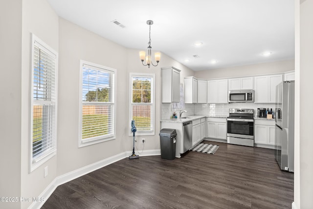 kitchen with sink, decorative light fixtures, appliances with stainless steel finishes, decorative backsplash, and white cabinets