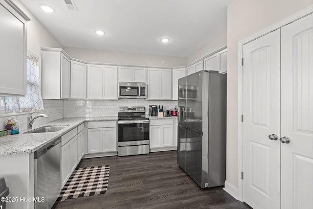 kitchen featuring sink, white cabinetry, tasteful backsplash, appliances with stainless steel finishes, and light stone countertops