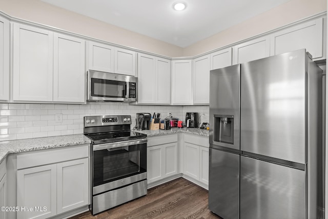 kitchen with dark wood-type flooring, light stone counters, tasteful backsplash, stainless steel appliances, and white cabinets