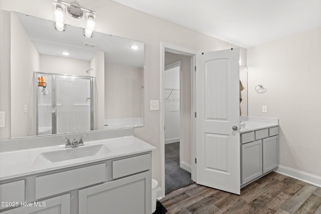 bathroom with walk in shower, vanity, and hardwood / wood-style flooring