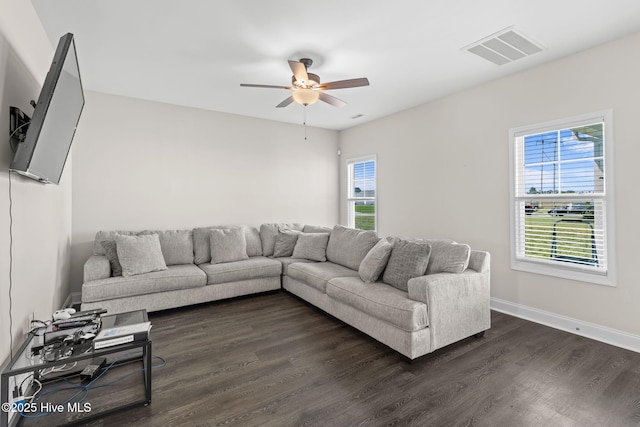 living room featuring dark wood-type flooring, ceiling fan, and plenty of natural light