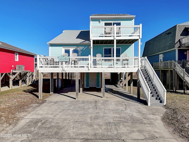 back of property with a balcony, a porch, and a carport