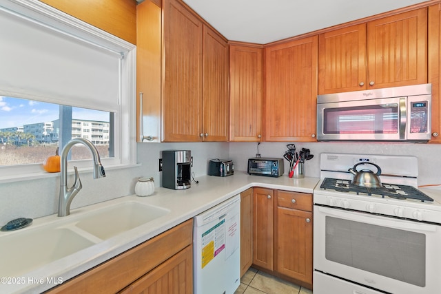 kitchen with light tile patterned flooring, white appliances, and sink