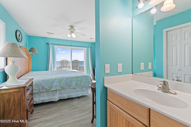 bedroom featuring access to outside, sink, light hardwood / wood-style flooring, ceiling fan, and a closet