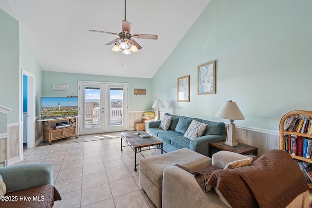 tiled living room with ceiling fan, high vaulted ceiling, and french doors