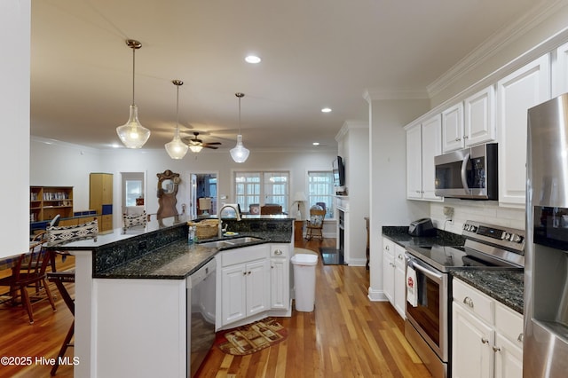 kitchen with white cabinets, a kitchen breakfast bar, sink, ceiling fan, and appliances with stainless steel finishes