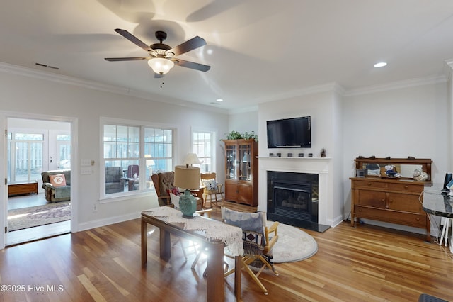 living room with ceiling fan, ornamental molding, and light hardwood / wood-style flooring