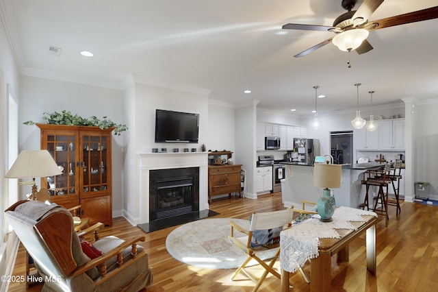 living room with ceiling fan, light hardwood / wood-style floors, and ornamental molding