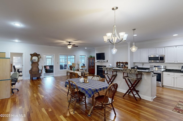 dining room featuring ceiling fan with notable chandelier, light wood-type flooring, and ornamental molding