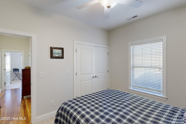 bedroom with ceiling fan, light wood-type flooring, and a closet