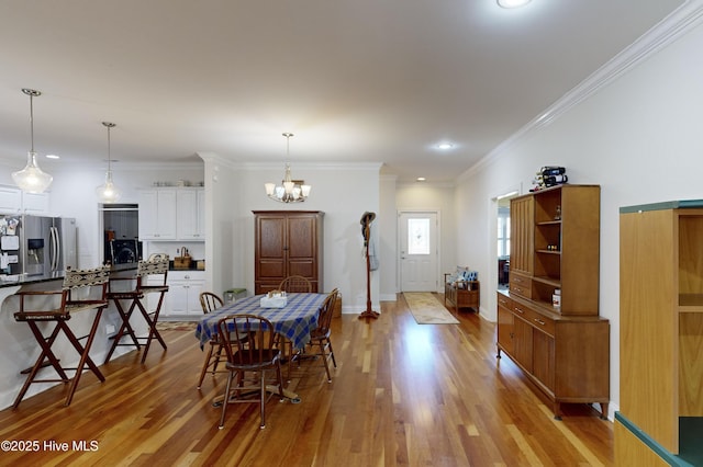 dining area featuring a chandelier, light wood-type flooring, and ornamental molding