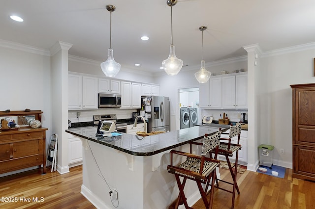 kitchen with white cabinets, washer and dryer, stainless steel appliances, and tasteful backsplash