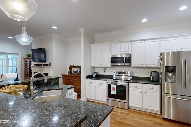 kitchen with stainless steel appliances, white cabinetry, hanging light fixtures, and sink