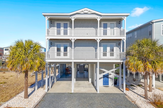 raised beach house featuring french doors, a balcony, and a carport