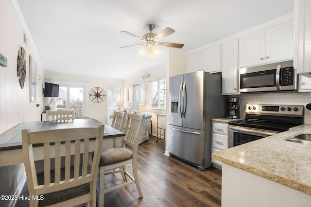 kitchen with crown molding, light stone countertops, appliances with stainless steel finishes, a healthy amount of sunlight, and white cabinetry