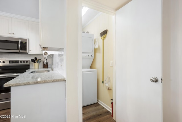 kitchen featuring white cabinetry, sink, light stone counters, stacked washer and dryer, and appliances with stainless steel finishes