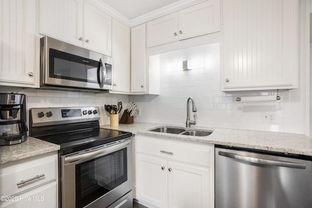 kitchen with backsplash, white cabinets, sink, appliances with stainless steel finishes, and light stone counters