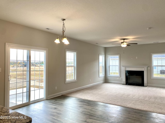 unfurnished living room featuring a textured ceiling, wood-type flooring, and ceiling fan with notable chandelier