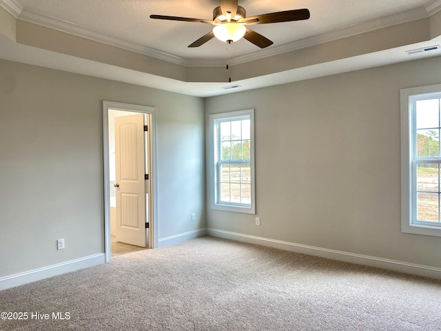 carpeted empty room with a raised ceiling, ceiling fan, and ornamental molding