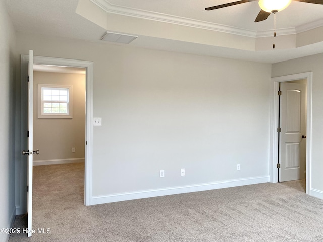 carpeted spare room featuring a tray ceiling, crown molding, and ceiling fan