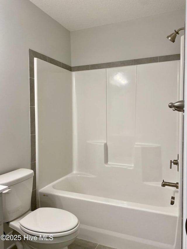 bathroom with a textured ceiling, tile patterned flooring, bathtub / shower combination, and toilet