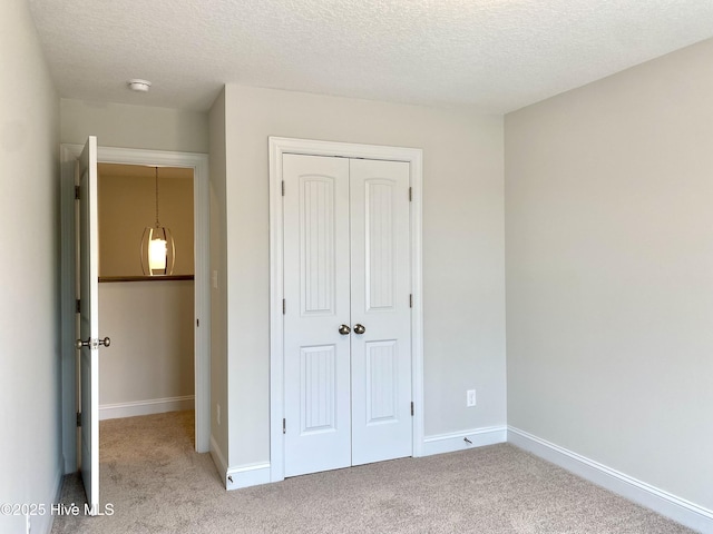 unfurnished bedroom with a textured ceiling, light carpet, and a closet