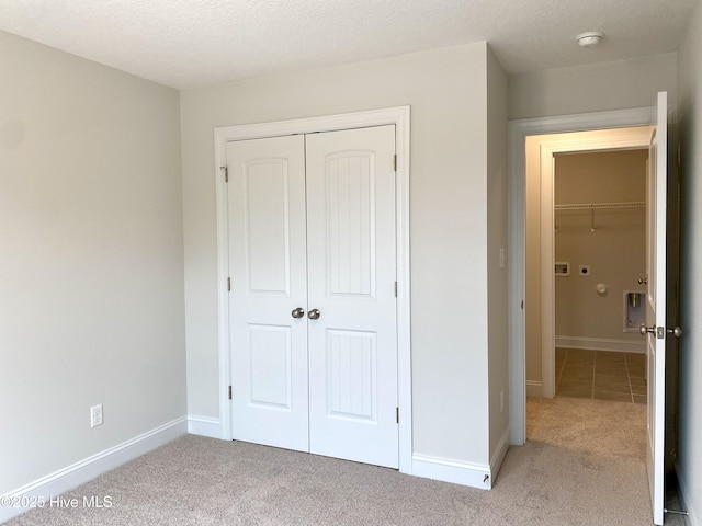 unfurnished bedroom featuring light carpet, a textured ceiling, and a closet