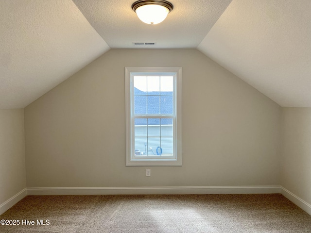 bonus room featuring carpet, lofted ceiling, and a textured ceiling