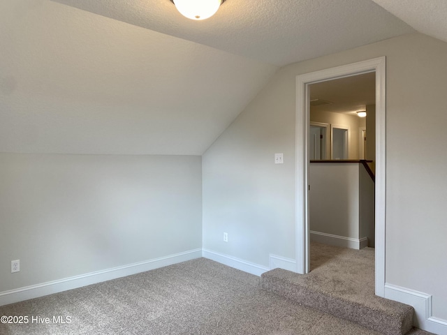 additional living space featuring a textured ceiling, carpet floors, and lofted ceiling