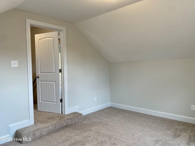 bonus room with carpet flooring, vaulted ceiling, and a textured ceiling