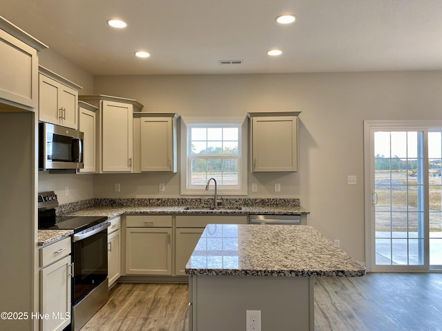 kitchen featuring a healthy amount of sunlight, light stone counters, sink, and stainless steel appliances