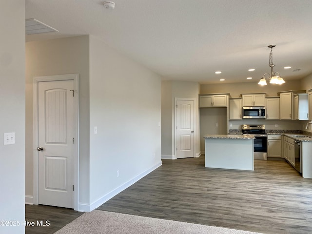 kitchen featuring a kitchen island, light stone countertops, hanging light fixtures, and appliances with stainless steel finishes