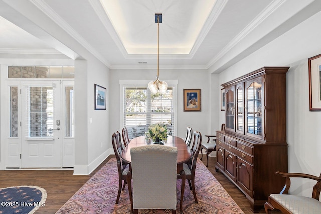 dining room featuring dark hardwood / wood-style flooring, ornamental molding, and a raised ceiling