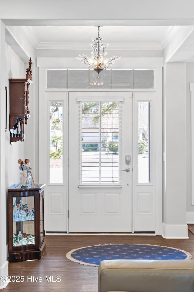 entryway with dark hardwood / wood-style flooring, crown molding, and an inviting chandelier