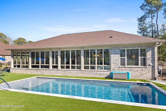 back of property with a lawn and a sunroom