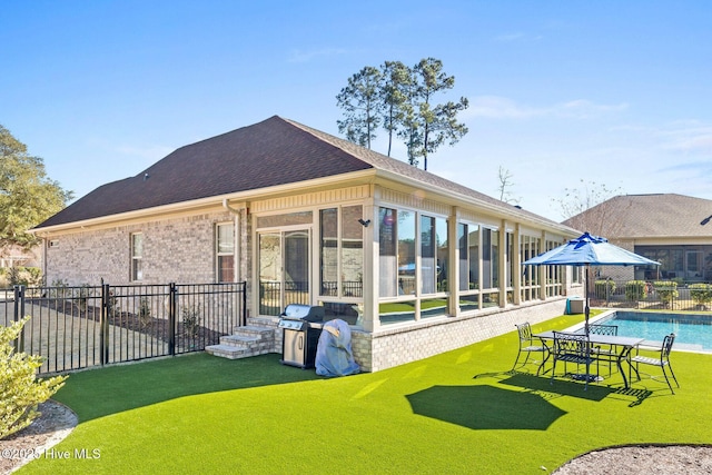 back of property with a yard, a fenced in pool, and a sunroom