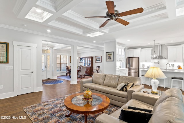 living room featuring coffered ceiling, beam ceiling, dark hardwood / wood-style flooring, ceiling fan with notable chandelier, and sink