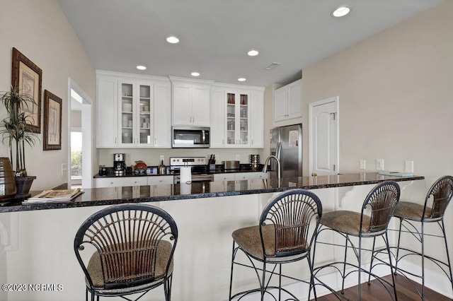 kitchen featuring white cabinets, a breakfast bar, kitchen peninsula, and stainless steel appliances