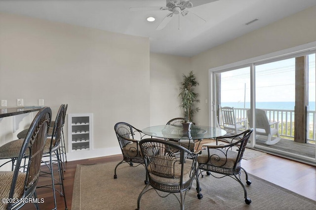 dining room with dark hardwood / wood-style flooring, ceiling fan, and a water view