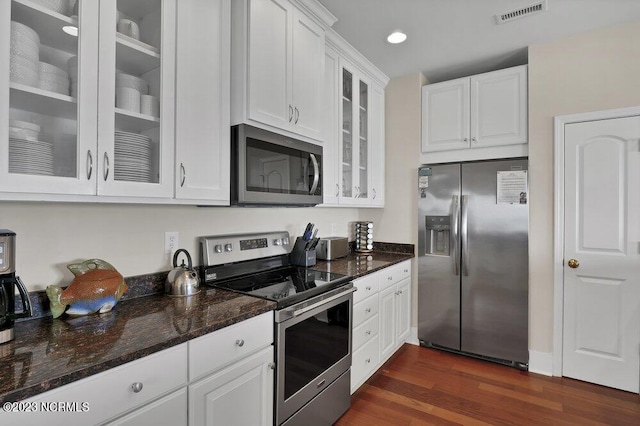 kitchen with white cabinets, stainless steel appliances, dark wood-type flooring, and dark stone counters