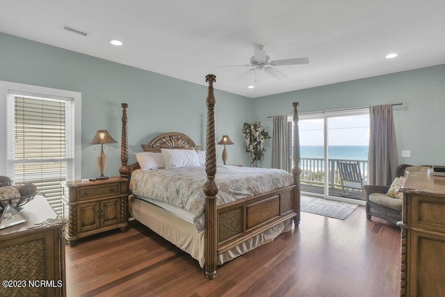 bedroom with access to exterior, ceiling fan, dark hardwood / wood-style floors, and a water view