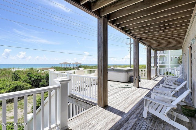 deck with a water view and a hot tub