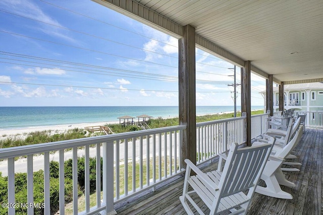 wooden deck featuring a porch, a water view, and a view of the beach