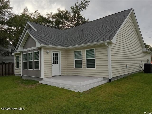 back of property featuring central AC unit and a lawn