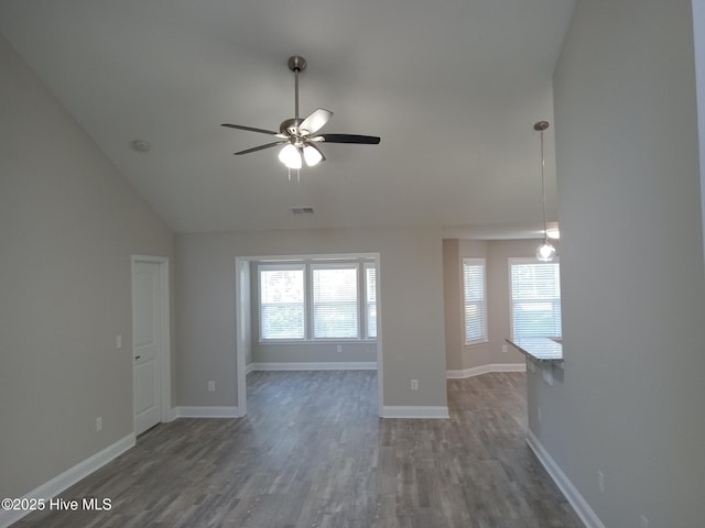 empty room with dark hardwood / wood-style floors, vaulted ceiling, and ceiling fan