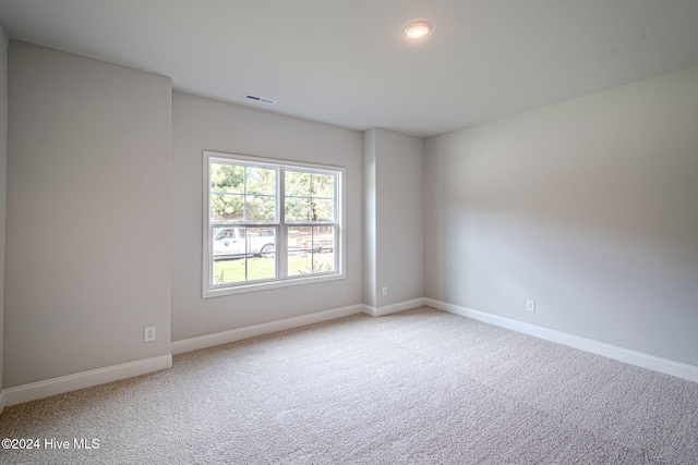 empty room featuring carpet floors, visible vents, and baseboards